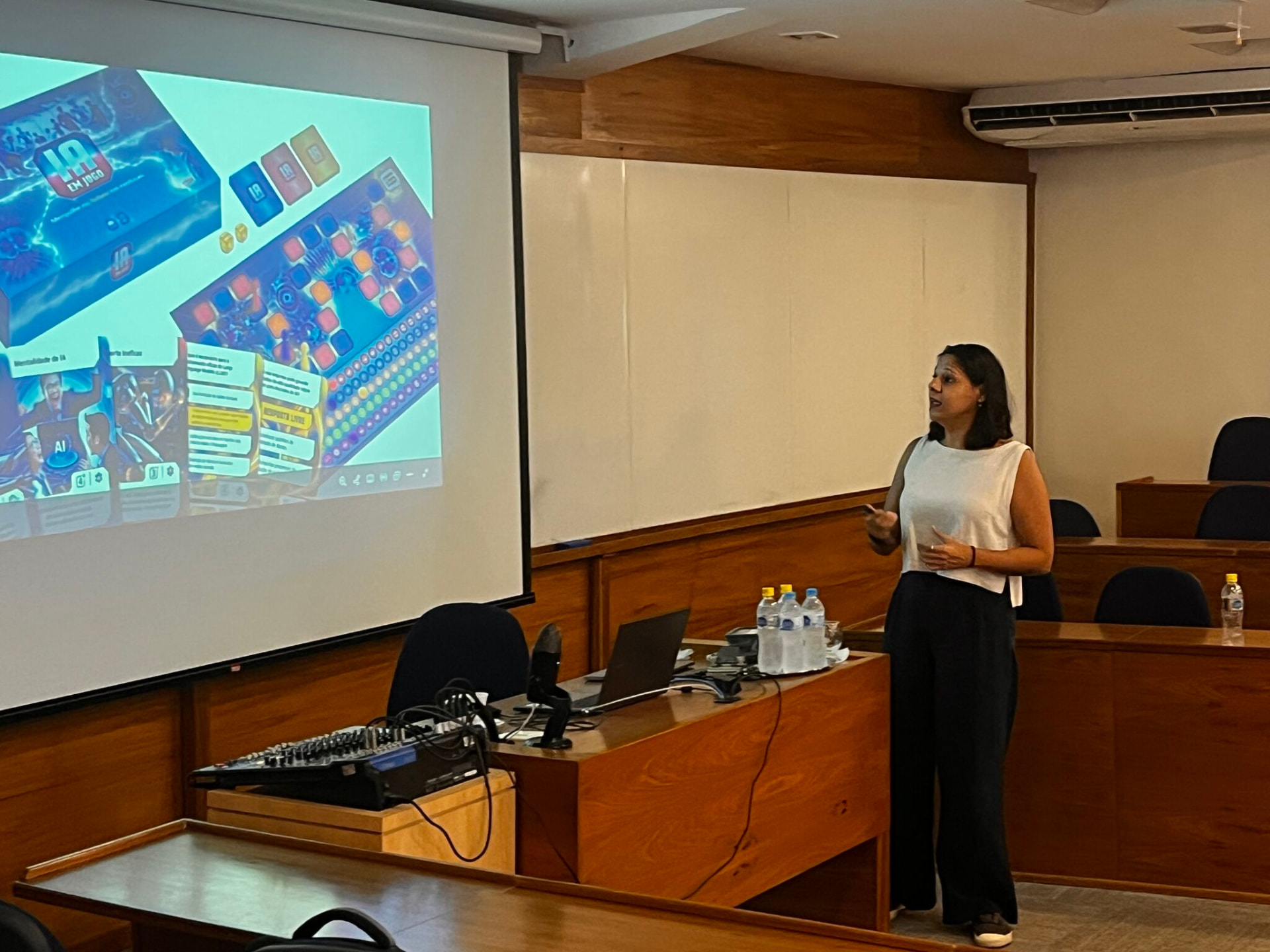 Luna Paladino apresentando em auditório com slide do IA EM JOGO projetado